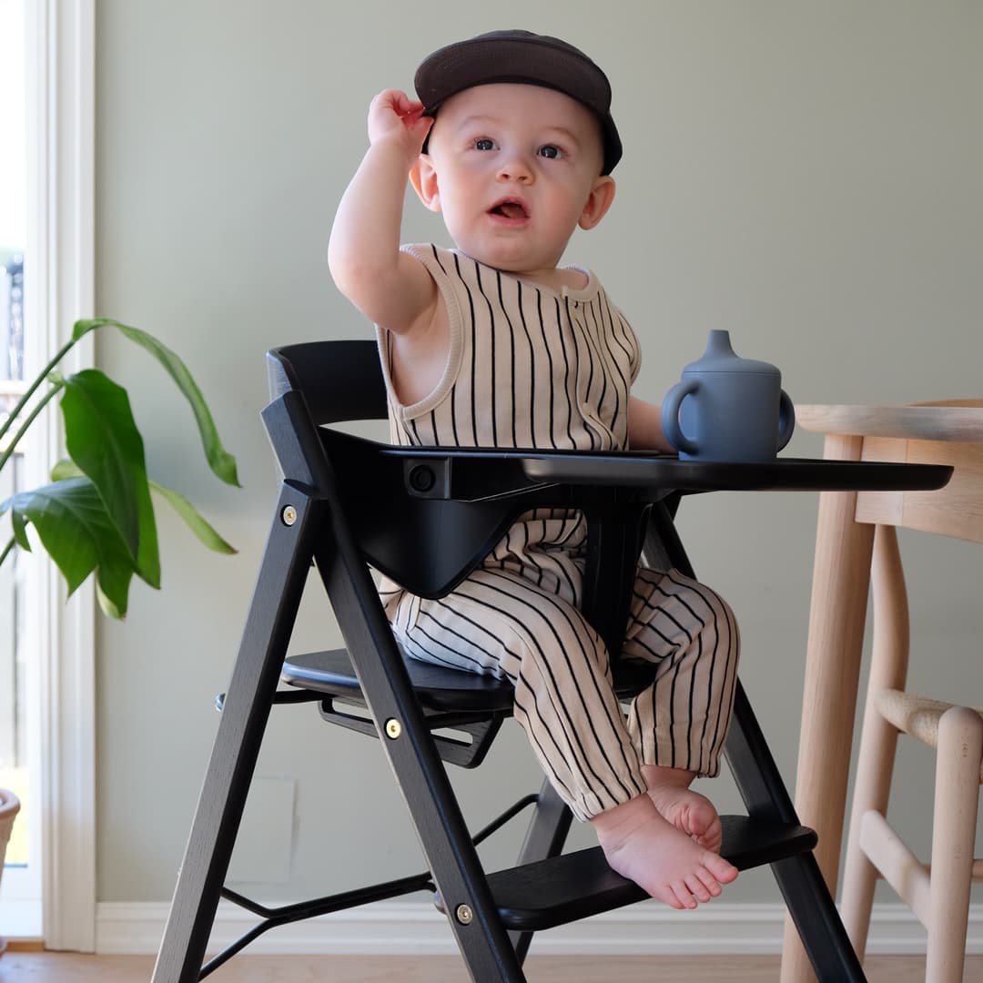 A baby sits in a KAOS KLAPP high chair
